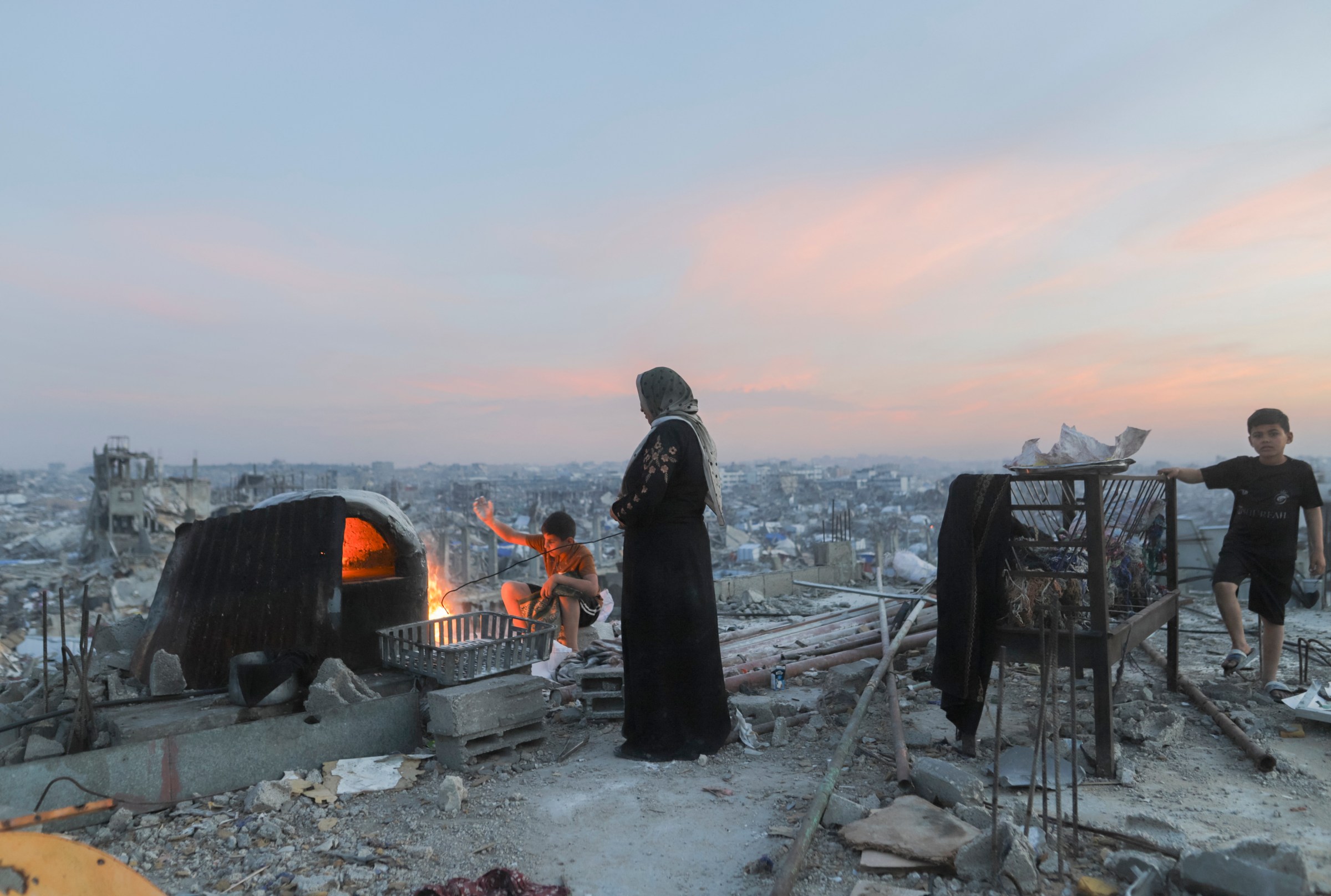 A Palestinian family cooks food on the roof of a partially demolished building in Beit Lahia, Gaza Strip, on March 17, 2025.